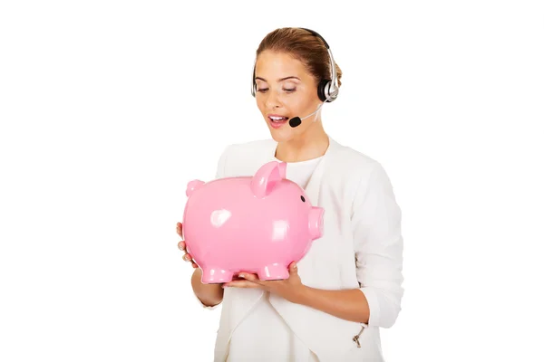 Jovem empresária em headset segurando piggybank — Fotografia de Stock