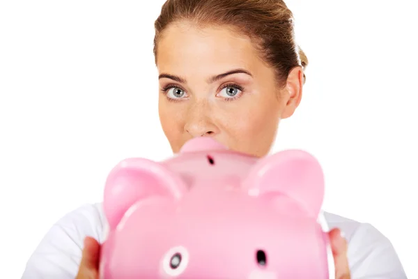 Young beautiful female doctor or nurse holding a piggybank — Stock Photo, Image