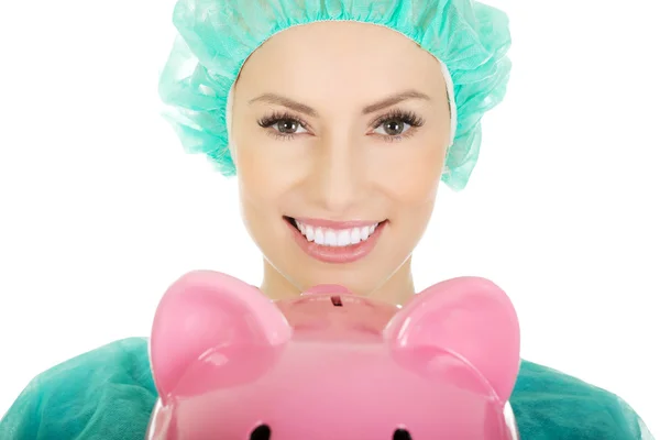 Female doctor with pink piggy bank. — Stock Photo, Image