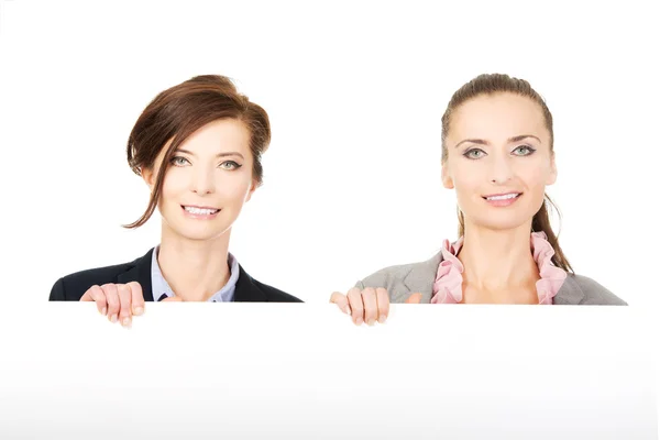 Två kvinnliga företagare transporterar en stor whiteboard. — Stockfoto