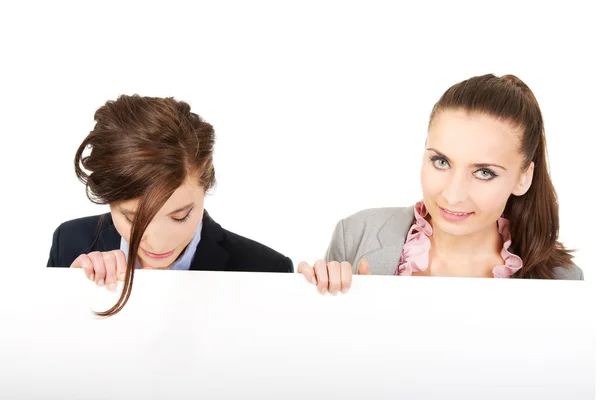 Two businesswomen carrying a big white board. — Stock Photo, Image