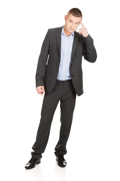 Businessman gesturing with finger against temple — Stock Photo, Image