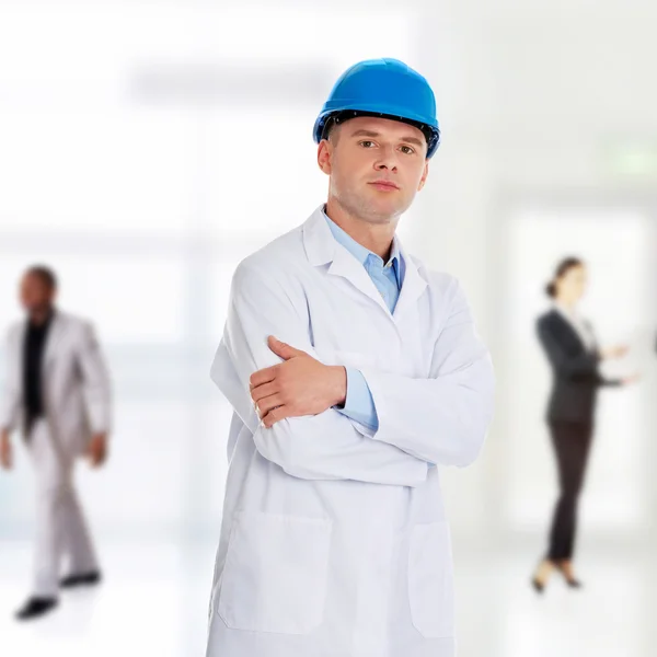 Hombre con una bata de laboratorio y casco — Foto de Stock