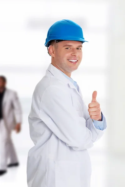 Hombre con una bata de laboratorio y casco —  Fotos de Stock