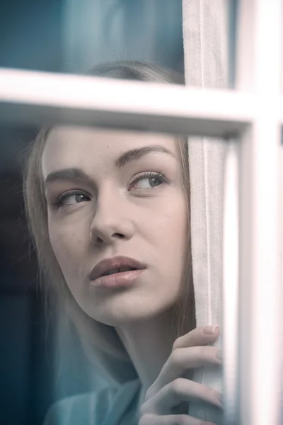 Hermosa mujer mirando por la ventana . — Foto de Stock