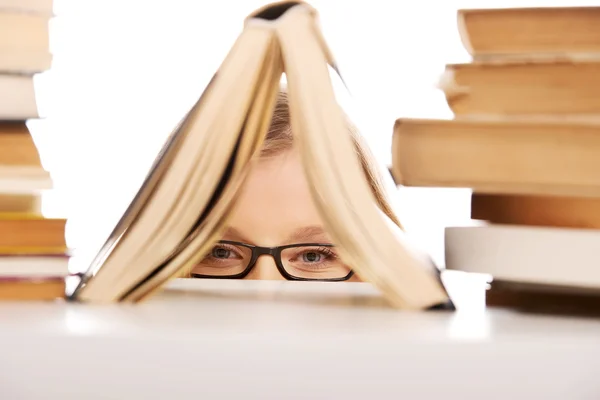 Ung kvinna gömmer sig bakom en bok — Stockfoto
