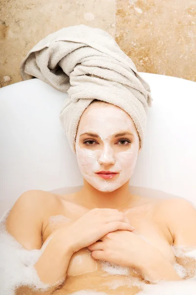 Frau entspannt sich in Badewanne mit Gesichtsmaske. — Stockfoto