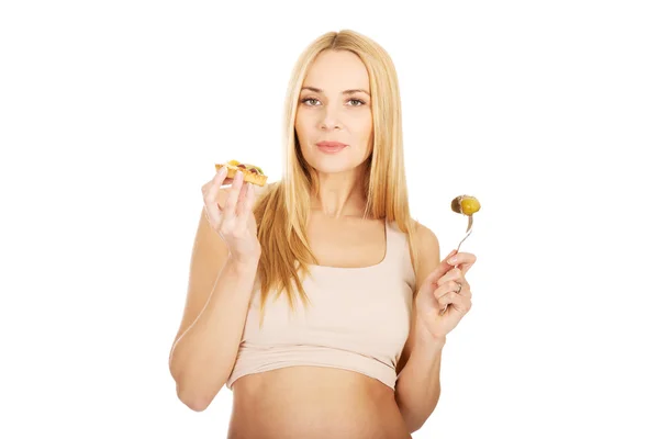 Счастливая беременная женщина с тортом и огурцами — стоковое фото