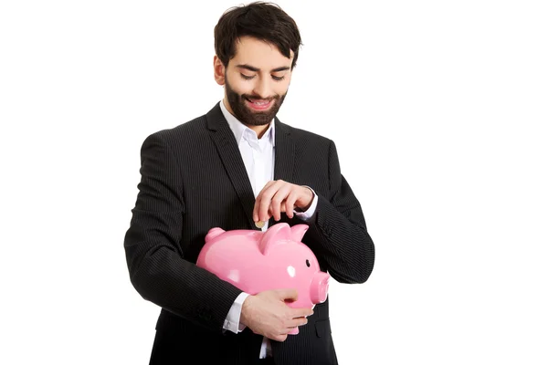 Businessman putting a coin to piggy bank. — Stock Photo, Image