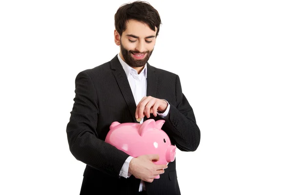 Empresario poniendo una moneda en la alcancía . —  Fotos de Stock