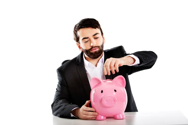 Businessman putting a coin to piggybank. — Stock Photo, Image