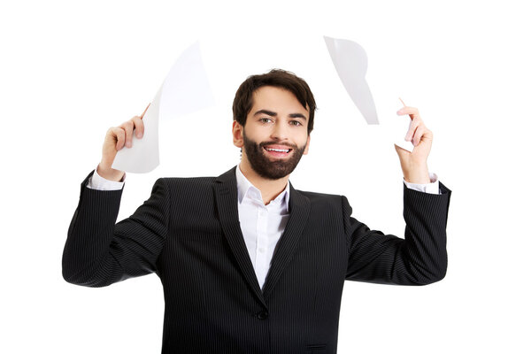 Happy businessman throwing paper sheets.