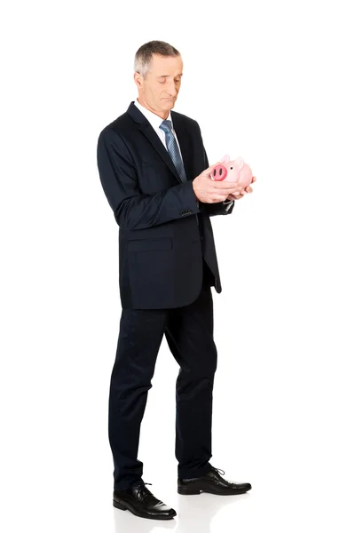 Full length confused businessman holding piggybank — Stock Photo, Image