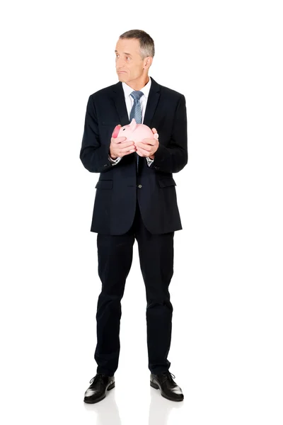 Full length confused businessman holding piggybank — Stock Photo, Image