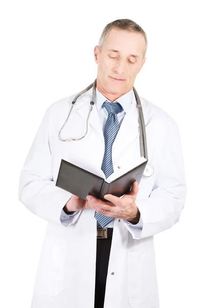 Mature male doctor reading notes — Stock Photo, Image