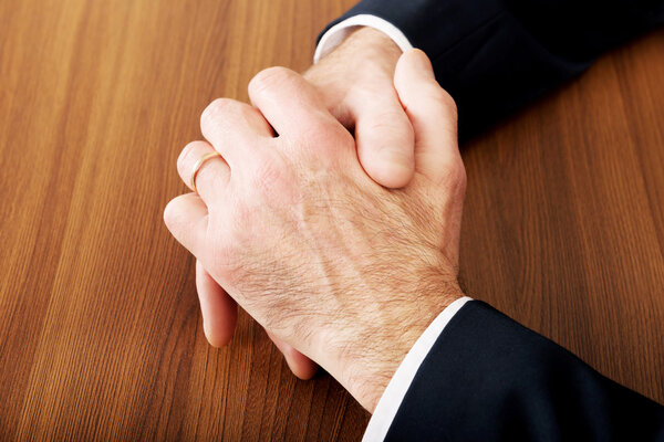 Close up of businessman clenched hands on the desk