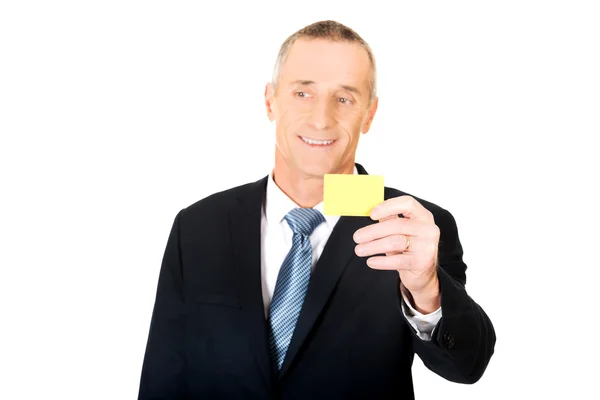 Empresário mostrando um cartão de identidade amarelo — Fotografia de Stock