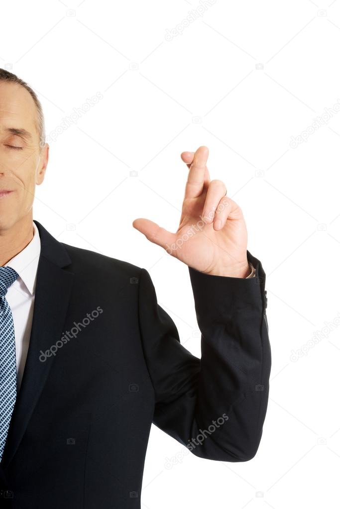 Businessman making a wish with fingers crossed