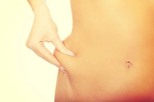 Štíhlá žena špetka její břicho. — Stock fotografie