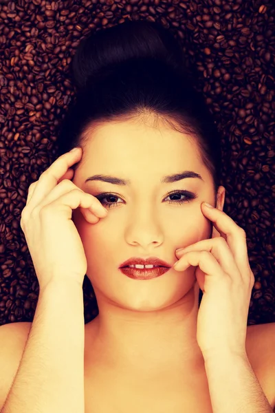 Attractive woman lying in coffee grains. — Stock Photo, Image