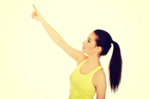 Hermosa mujer en ropa deportiva apuntando hacia arriba . — Foto de Stock