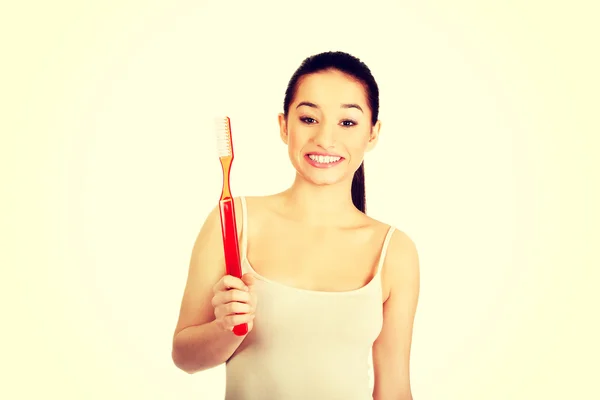 Mujer joven sosteniendo un cepillo de dientes grande . —  Fotos de Stock