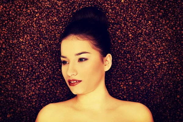Attractive woman lying in coffee grains. — Stock Photo, Image