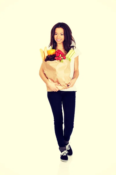 Ung kvinna med livsmedelsbutiker och grönsaker. — Stockfoto