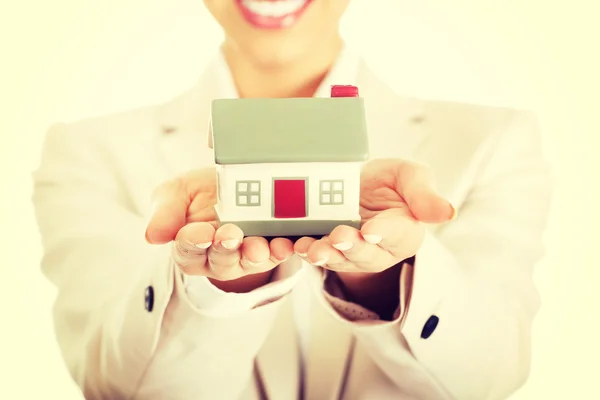 Businesswoman holding small house on palm. — Stock Photo, Image