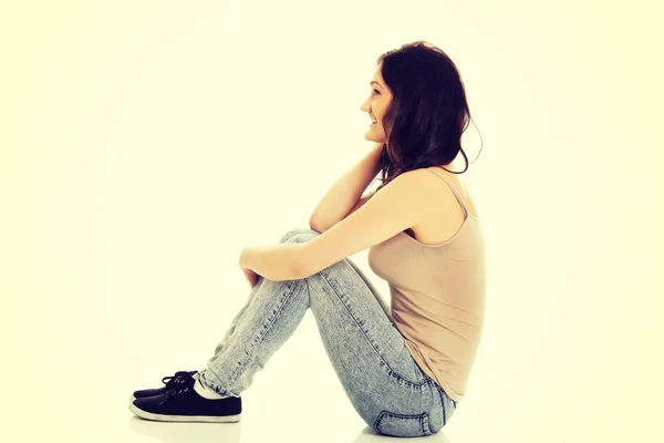 Młoda kobieta uśmiechający się, siedząc na podłodze. — Zdjęcie stockowe