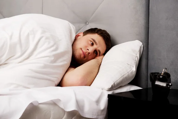 Schöner junger Mann liegt im Bett. — Stockfoto