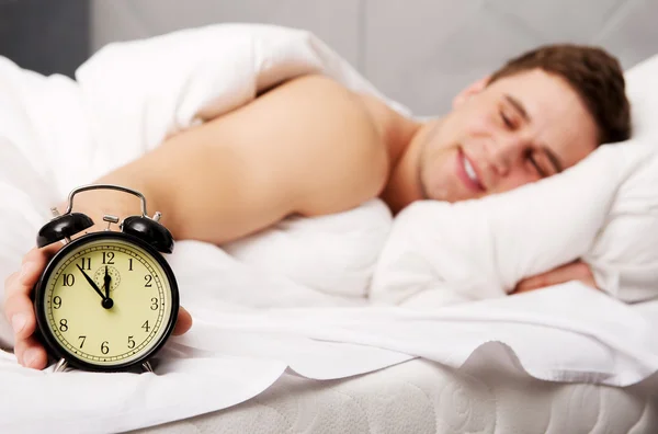 Man with alarm clock in bedroom. — Stock Photo, Image