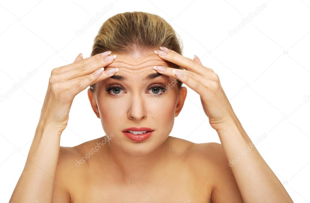 A young woman checking wrinkles on her forehead
