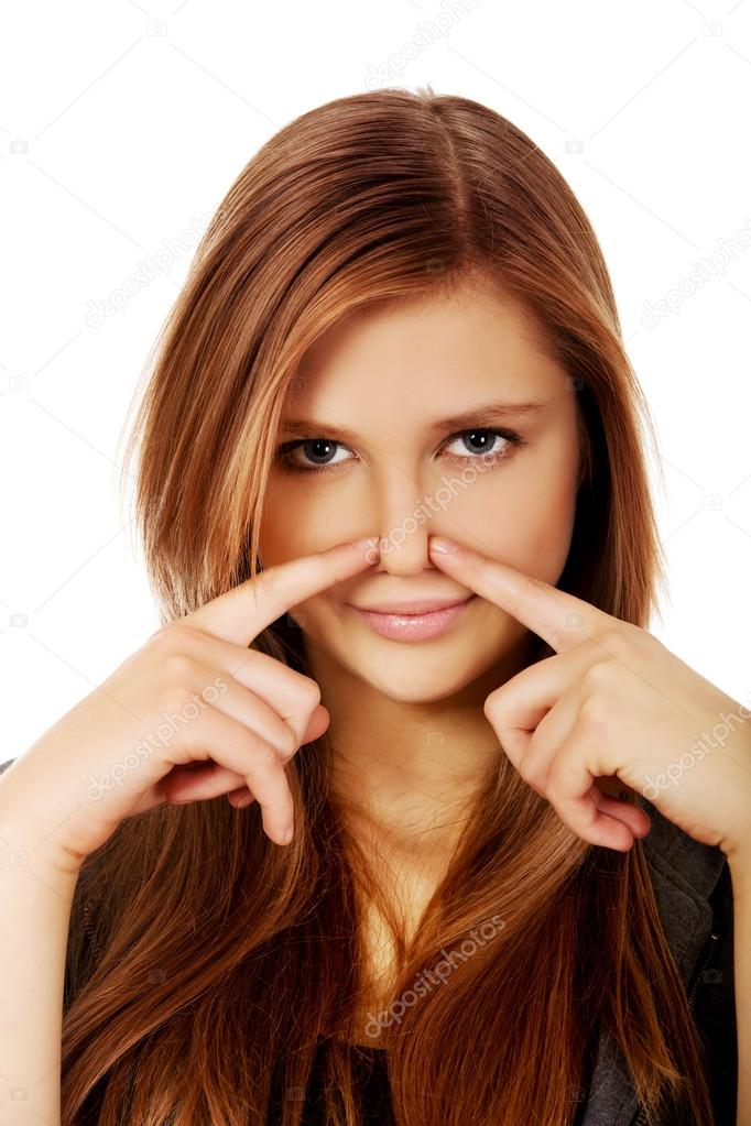 Young woman pinches nose with fingers hands looks