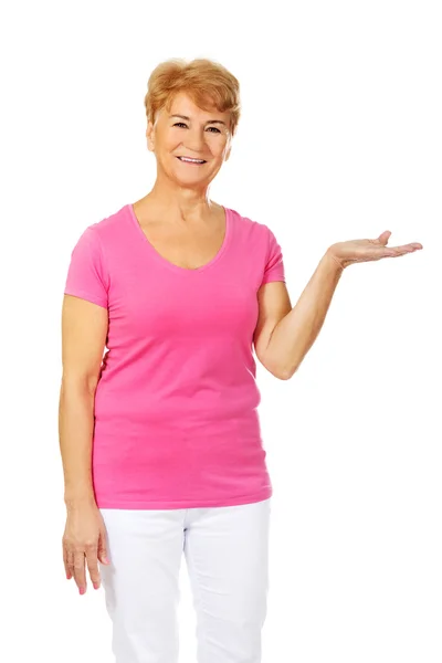 Uma velha mulher sorrindo apresentando algo — Fotografia de Stock