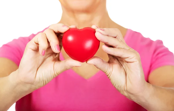 Vieja mujer sosteniendo rojo juguete corazón — Foto de Stock