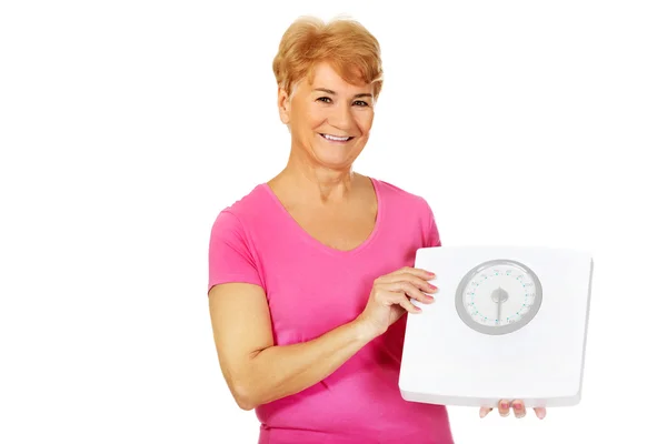 Smiling old woman holding weight scale — Stock Photo, Image