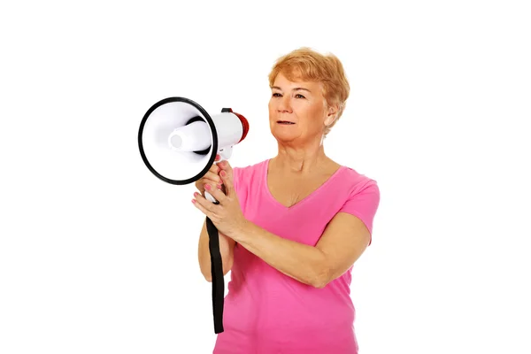 Senior lachende vrouw schreeuwen via een megafoon — Stockfoto