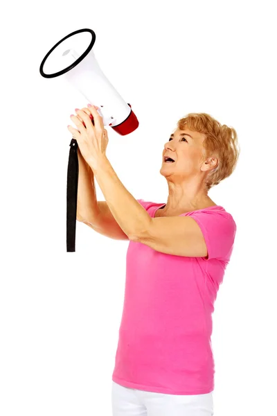 Senior lachende vrouw schreeuwen via een megafoon — Stockfoto