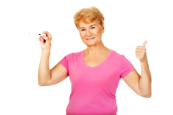 Старшая женщина показывает термометр и жесты ОК — стоковое фото