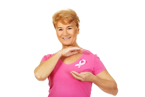 Smiling senior woman with breast cancer awareness ribbon — Stock Photo, Image