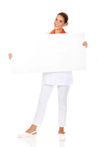 Szczęśliwa kobieta lekarz lub pielęgniarka trzyma pusty baner — Zdjęcie stockowe