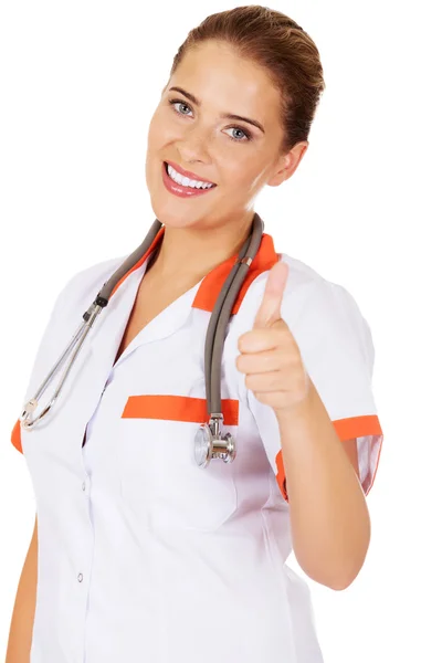 Jovem sorriso feminino médico ou enfermeira mostra polegar para cima — Fotografia de Stock