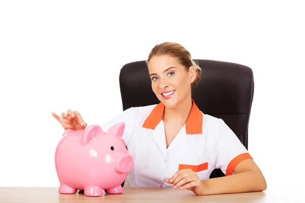 Lachende arts met piggy bank — Stockfoto