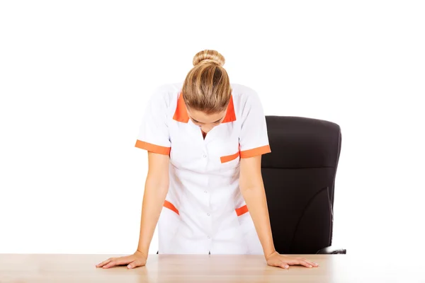 Médico cansado parado detrás del escritorio —  Fotos de Stock