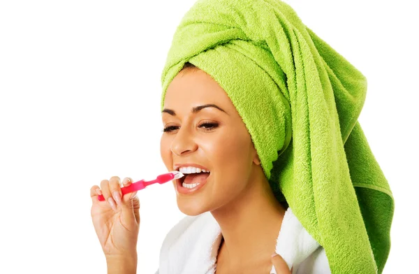 Woman in bathrobe brushing teeth — Stock Photo, Image