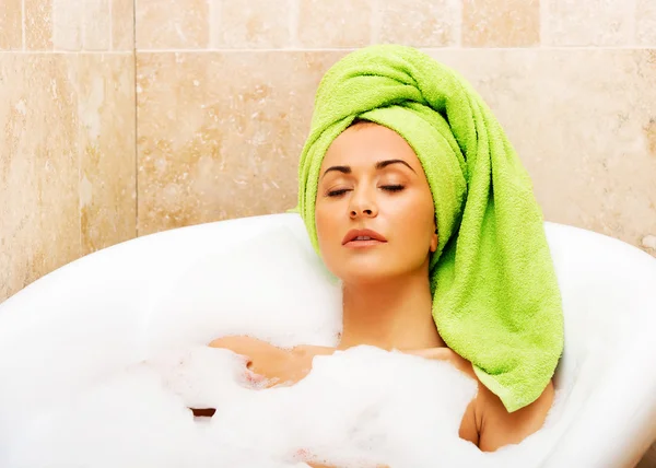 Mulher relaxante no banho com os olhos fechados — Fotografia de Stock