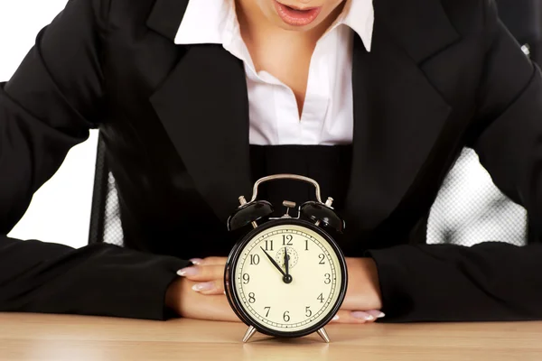 Affärskvinna med väckarklocka bakom skrivbordet — Stockfoto
