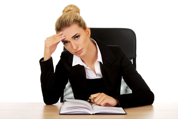 Mujer de negocios cansada escribiendo nota junto a un escritorio —  Fotos de Stock