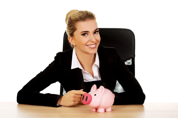 Geschäftsfrau mit Sparschwein hinter dem Schreibtisch — Stockfoto